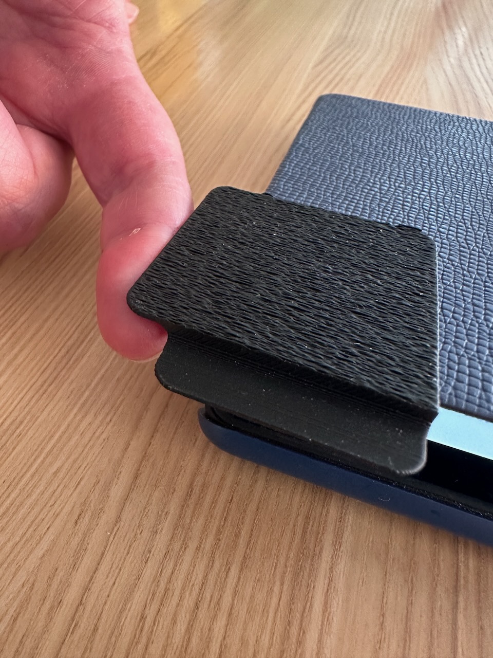 Finger, der mit der Öffnungshilfe den Deckel der Hülle anhebt