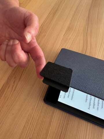 Finger hebt Hülle an mit Hilfe
